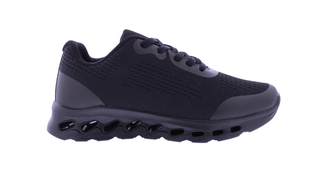 A black athletic sneaker with a textured mesh upper, matching black laces, and a distinctive wavy, hollow black sole, shown from a side profile on a white background.